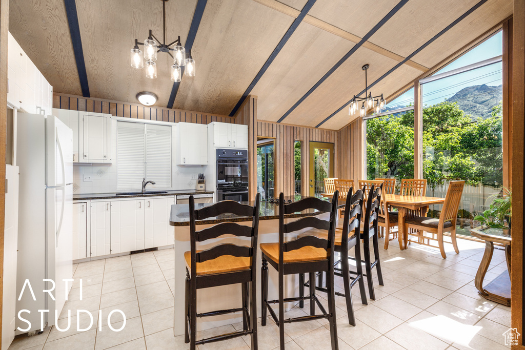 Dining room with a chandelier, light tile patterned floors, wooden walls, lofted ceiling, and a mountain view