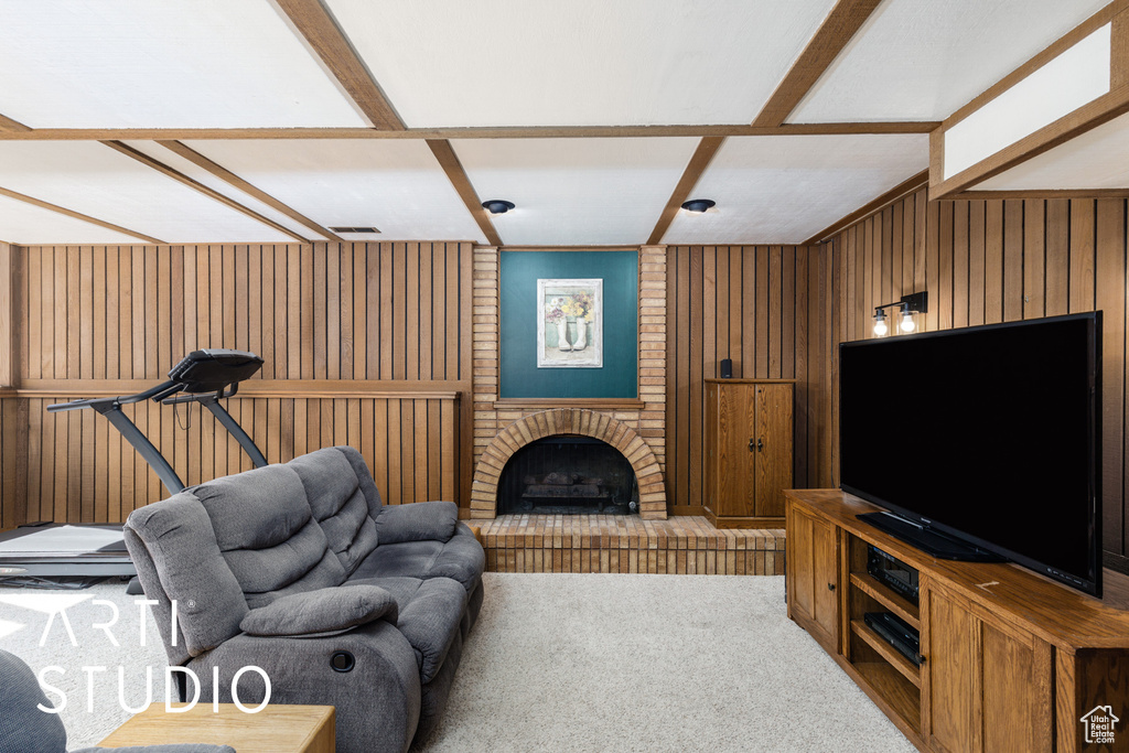 Carpeted living room featuring wooden walls, a brick fireplace, and coffered ceiling