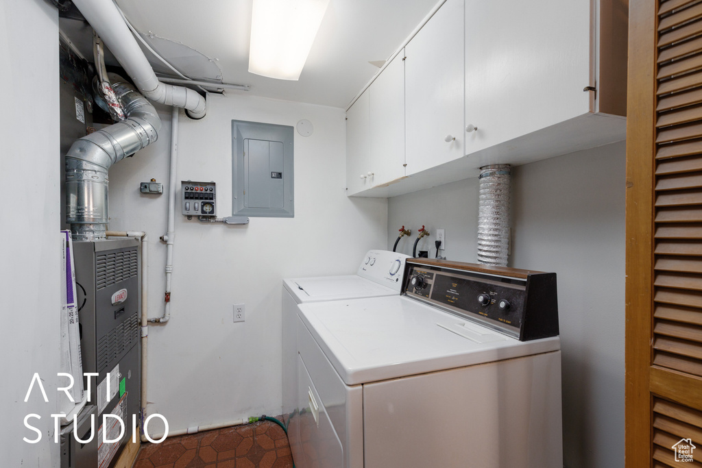 Laundry room with cabinet space, electric panel, washer and dryer, and tile patterned floors