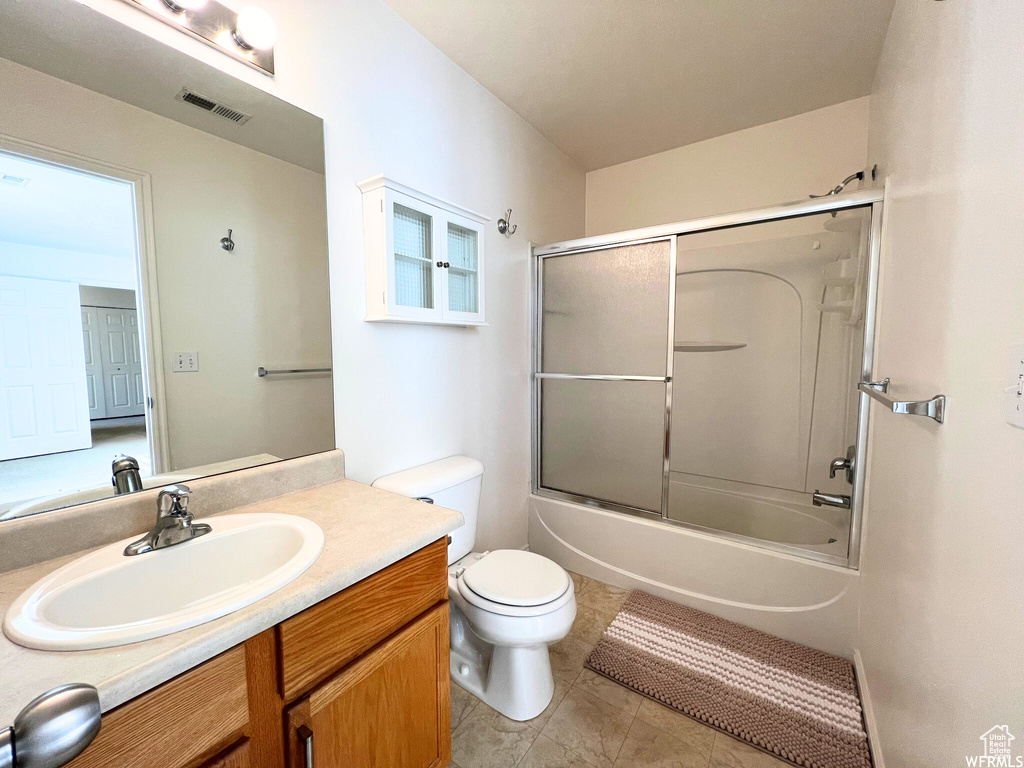 Bathroom featuring toilet, vanity, combined bath / shower with glass door, and tile patterned flooring