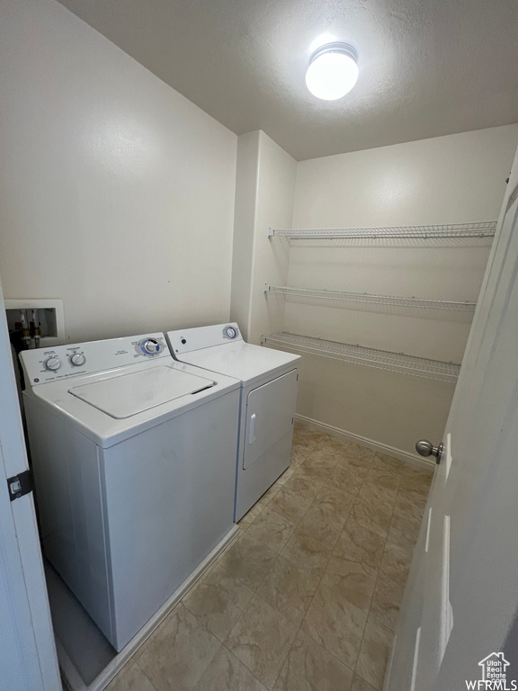 Washroom with washer and clothes dryer and a textured ceiling