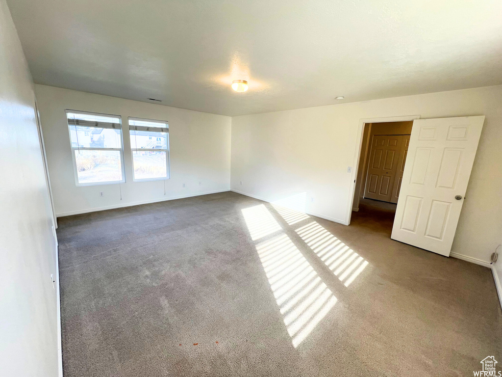 Carpeted spare room featuring baseboards