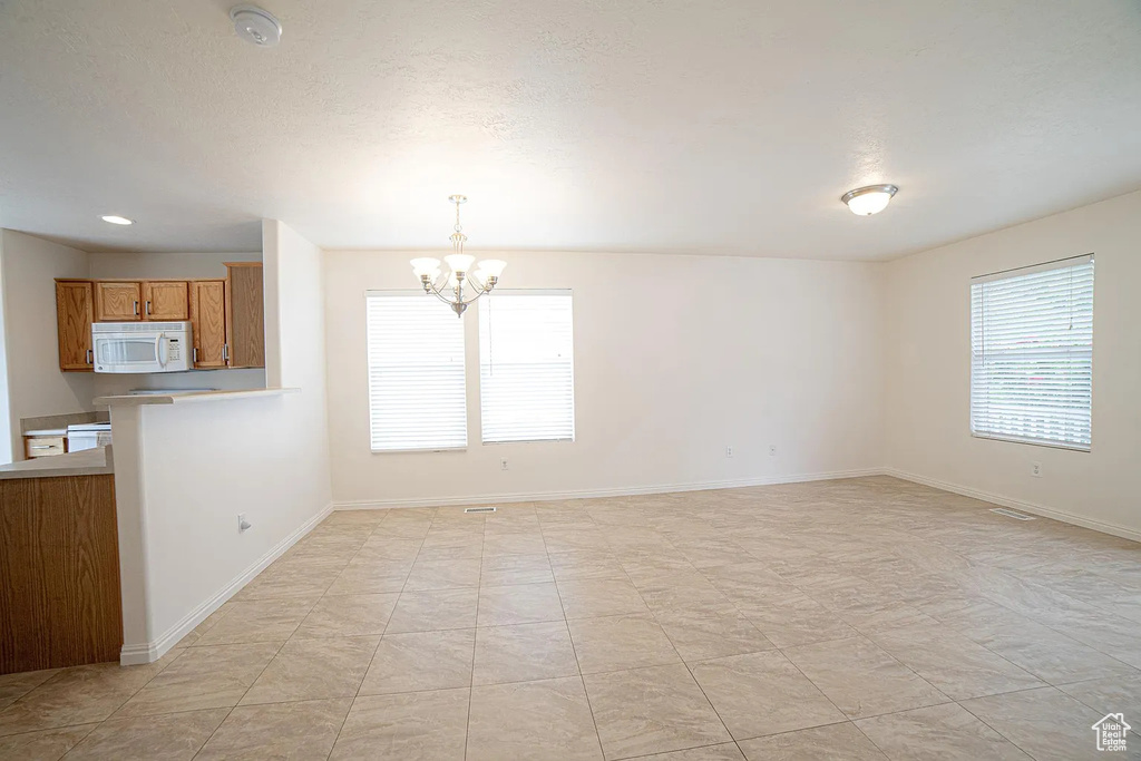 Unfurnished dining area with a chandelier and baseboards