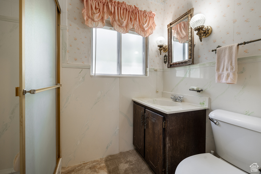 Bathroom featuring wallpapered walls, vanity, toilet, and wainscoting