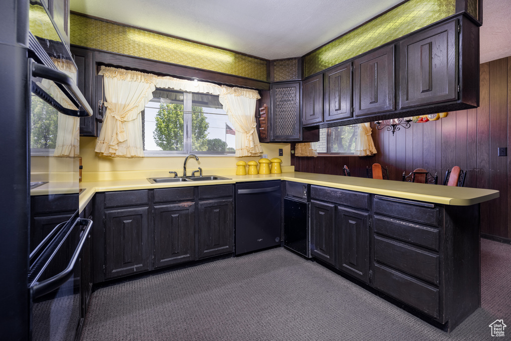 Kitchen featuring black dishwasher, dark carpet, a sink, light countertops, and a peninsula
