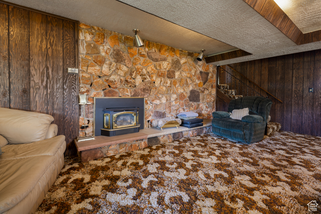 Carpeted living room featuring wooden walls, a textured ceiling, and a fireplace