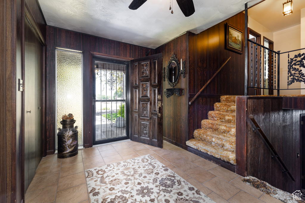 Entryway with wooden walls, stairs, and ceiling fan
