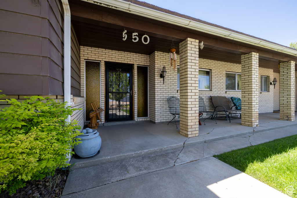 View of exterior entry featuring a porch and brick siding