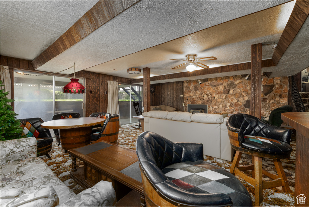 Living room featuring a textured ceiling, wooden walls, and a ceiling fan