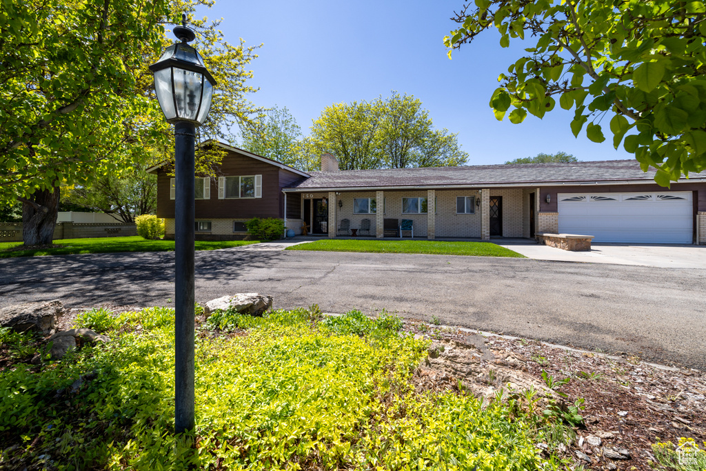 View of front of property with driveway, an attached garage, a chimney, and brick siding