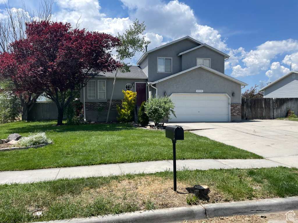 View of front of house with concrete driveway, brick siding, stucco siding, and an attached garage