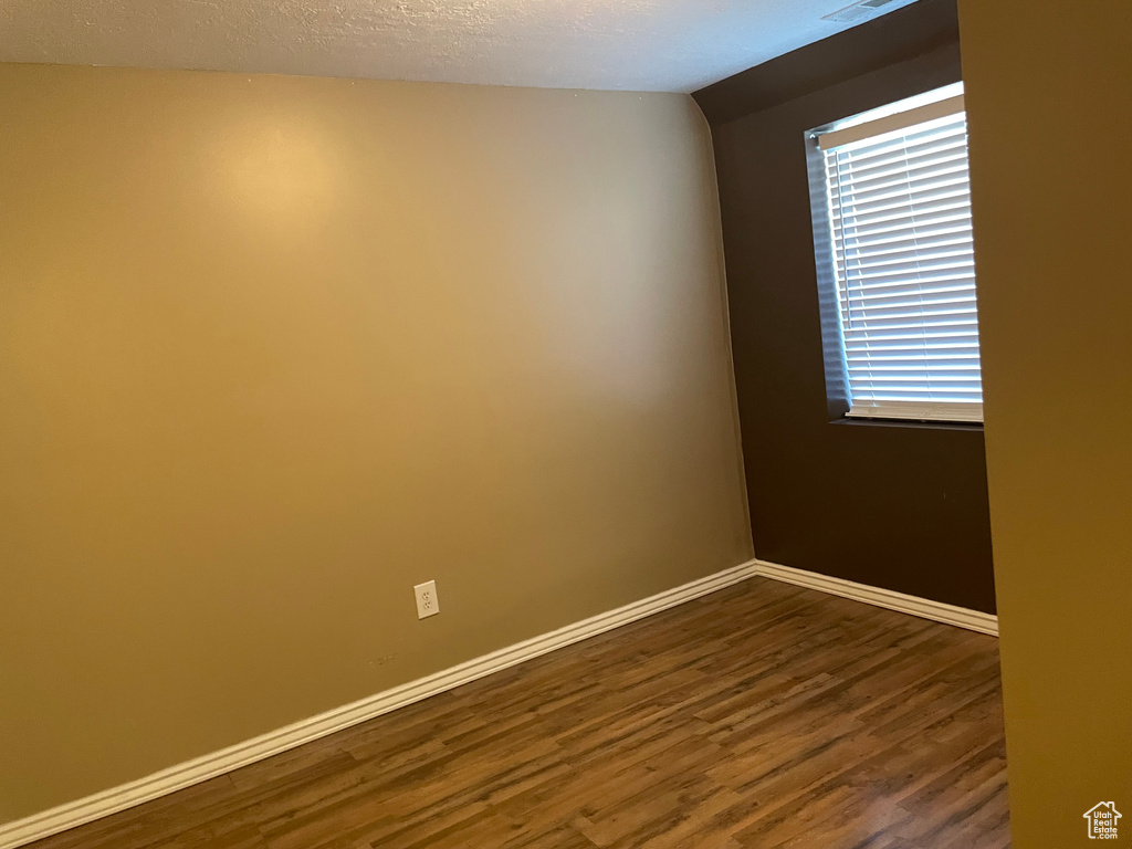 Spare room with dark wood-type flooring and baseboards
