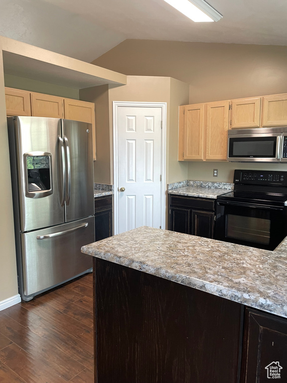 Kitchen featuring appliances with stainless steel finishes, light brown cabinets, vaulted ceiling, dark wood finished floors, and baseboards