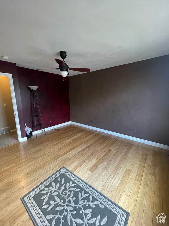 Spare room featuring a ceiling fan, wood finished floors, and baseboards