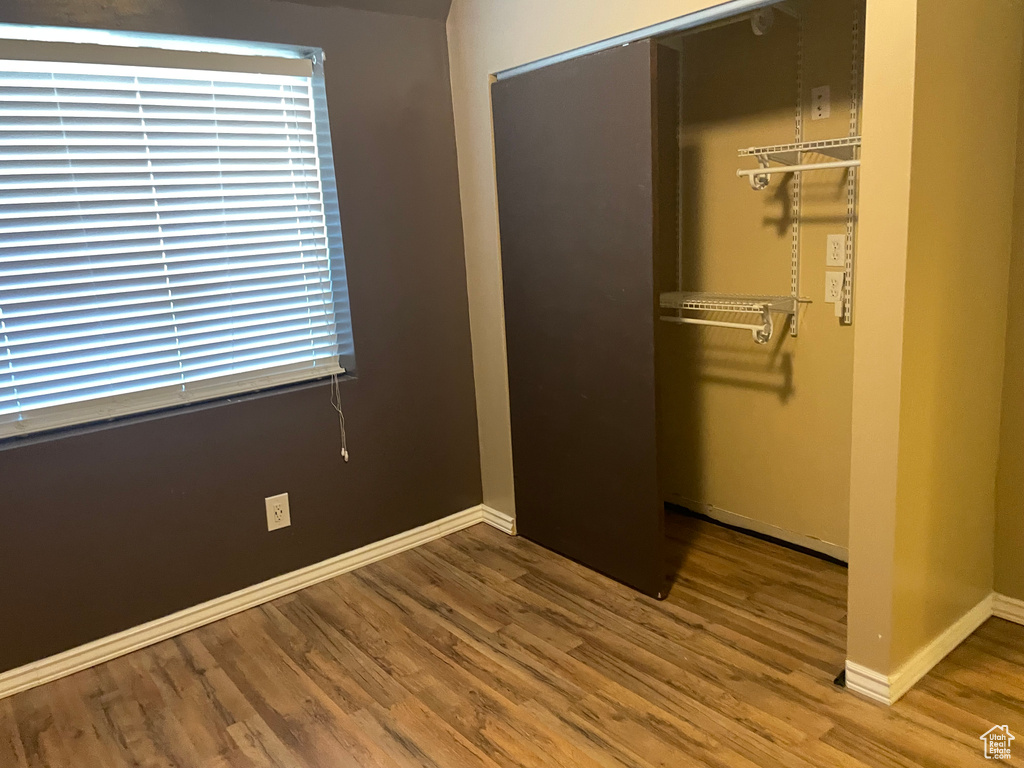 Unfurnished bedroom with a closet, wood finished floors, and baseboards