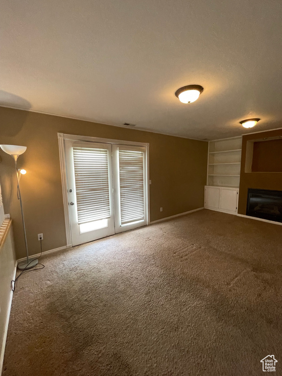 Unfurnished living room featuring carpet flooring, baseboards, a fireplace, and built in features
