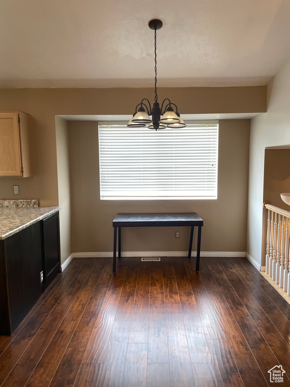 Dining area with a chandelier, healthy amount of natural light, baseboards, and dark wood-style floors