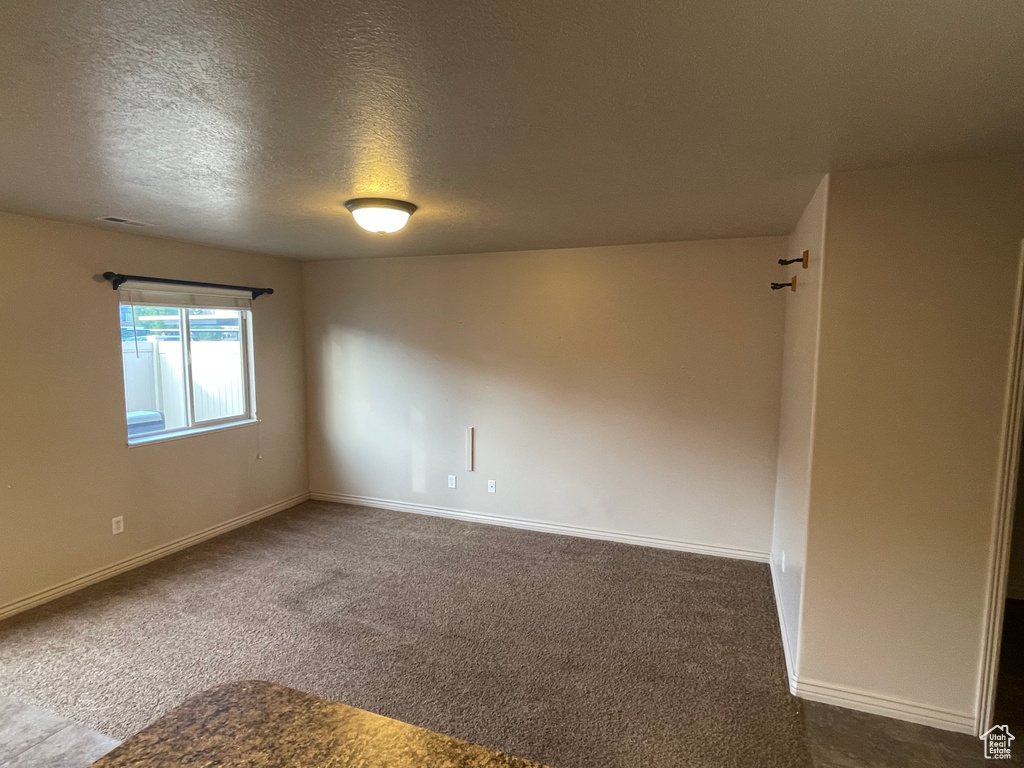 Carpeted empty room featuring baseboards and a textured ceiling
