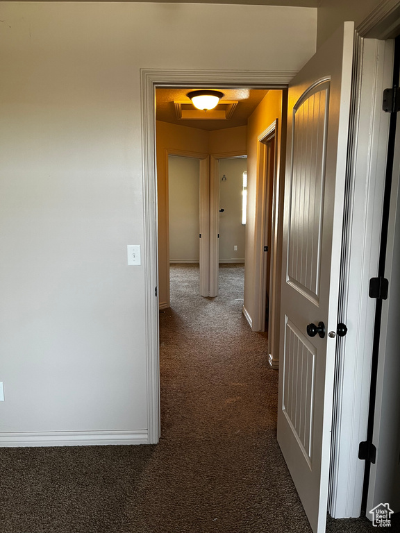 Hall with dark carpet and baseboards