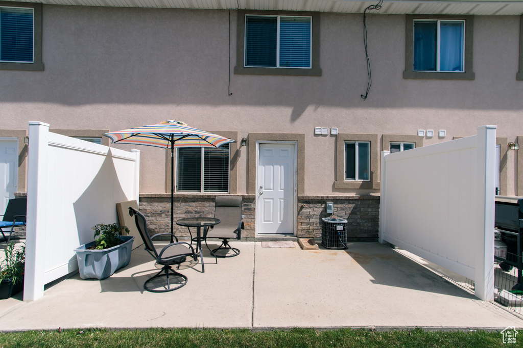 Rear view of property featuring a patio area, stucco siding, and stone siding