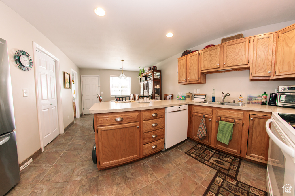 Kitchen with white appliances, a sink, a peninsula, light countertops, and recessed lighting