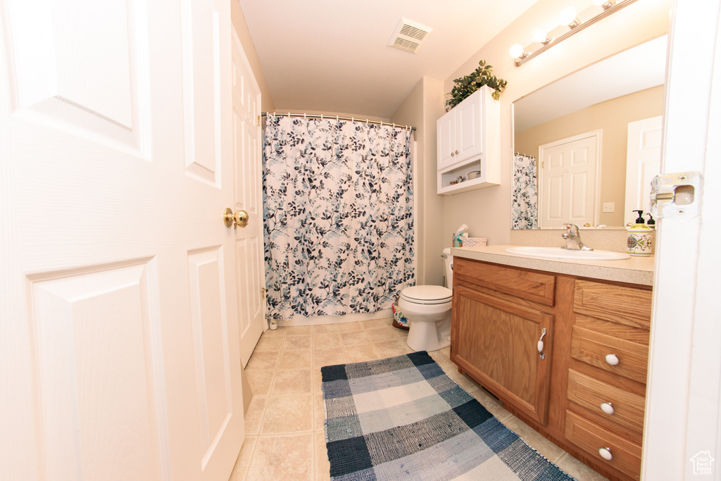 Full bathroom with vanity, tile patterned floors, toilet, and a shower with shower curtain