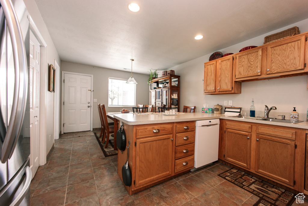 Kitchen with dishwasher, a sink, freestanding refrigerator, a peninsula, and light countertops