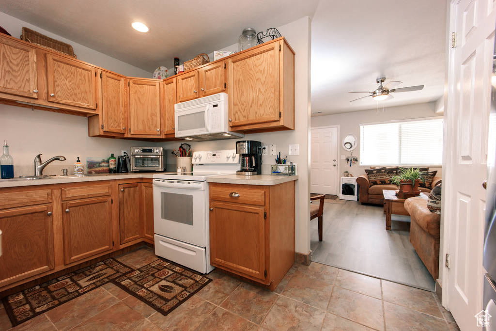 Kitchen featuring white appliances, a ceiling fan, light countertops, a sink, and recessed lighting