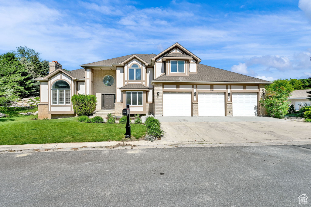 View of front facade with concrete driveway, a front lawn, and a garage