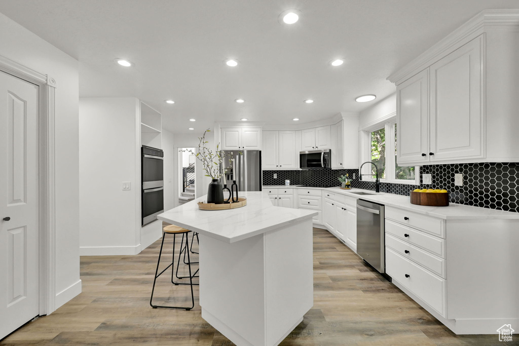 Kitchen featuring stainless steel appliances, a sink, white cabinetry, and recessed lighting