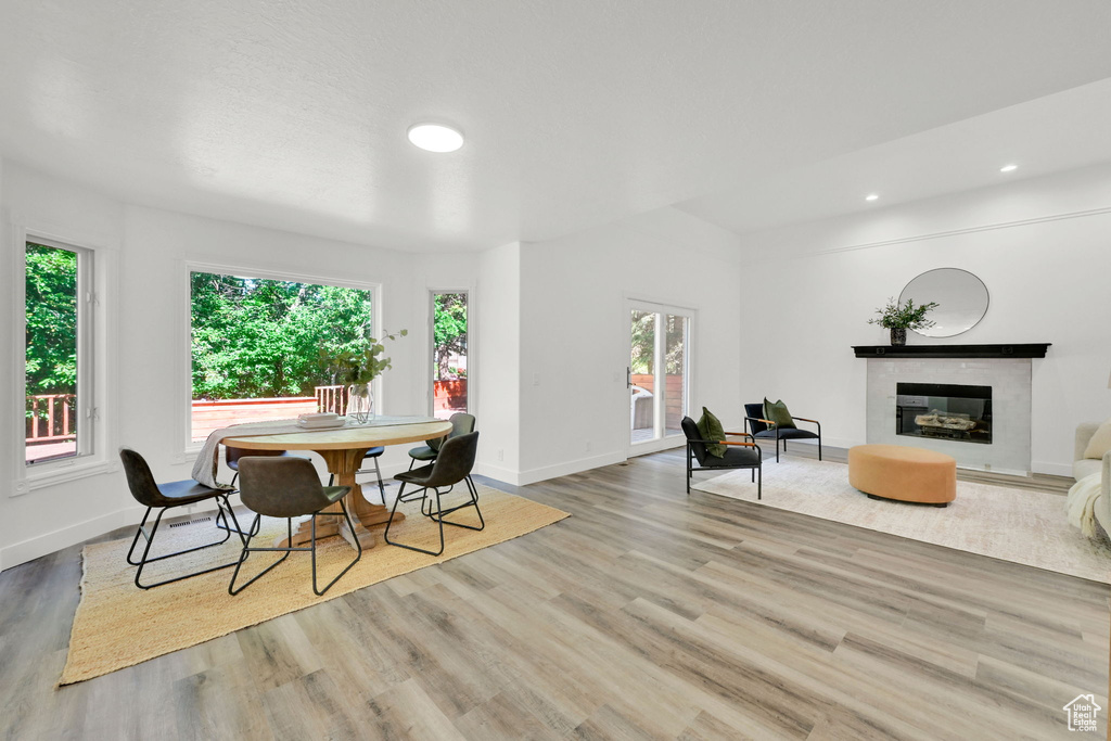 Dining space with wood finished floors, a glass covered fireplace, baseboards, and recessed lighting