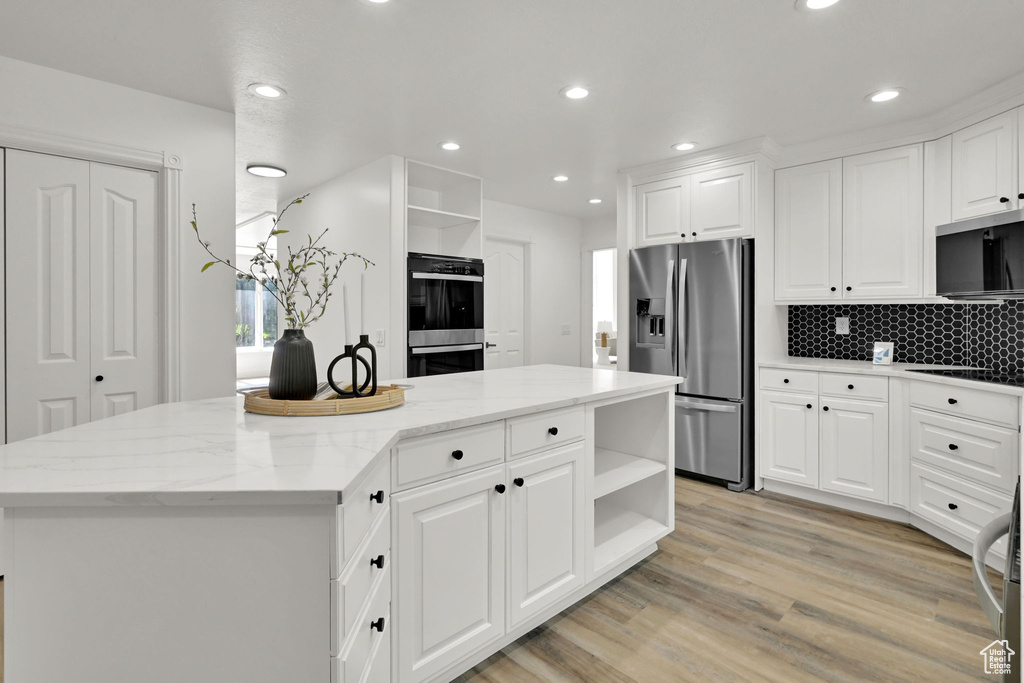 Kitchen featuring appliances with stainless steel finishes, open shelves, a kitchen island, recessed lighting, and white cabinetry