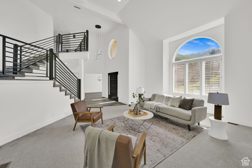 Living area with high vaulted ceiling, stairs, baseboards, and carpet floors