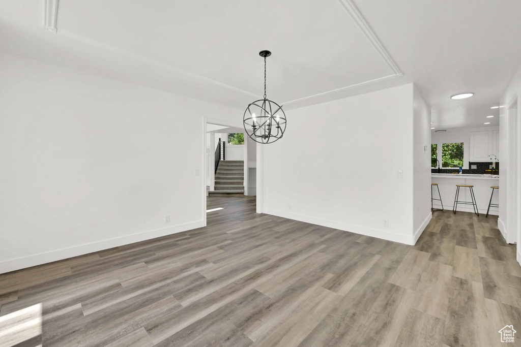 Unfurnished dining area featuring stairway, a chandelier, light wood-type flooring, baseboards, and recessed lighting