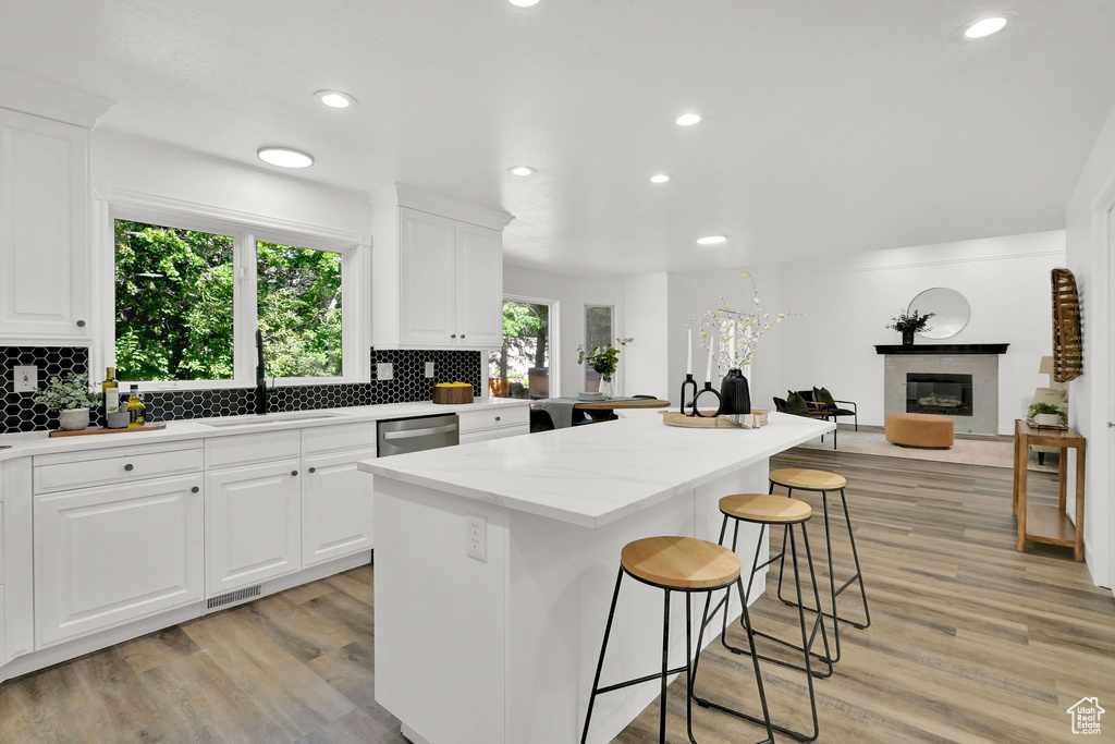 Kitchen with a kitchen bar, a sink, a glass covered fireplace, stainless steel dishwasher, and recessed lighting