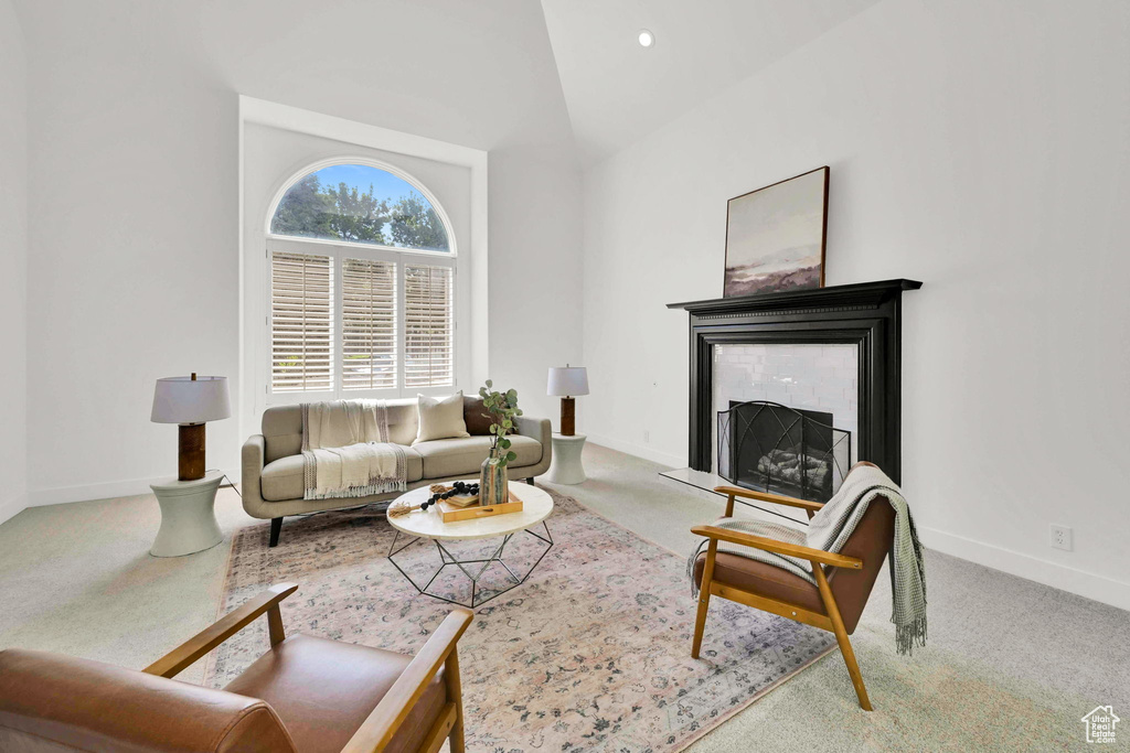 Carpeted living area featuring a tile fireplace, baseboards, and lofted ceiling
