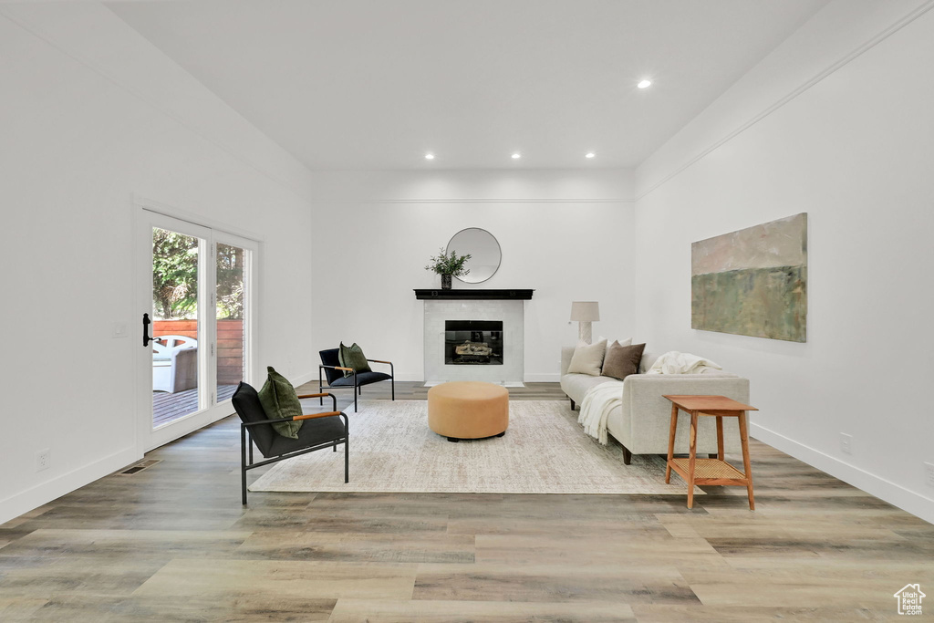 Living area with recessed lighting, wood finished floors, baseboards, and a glass covered fireplace