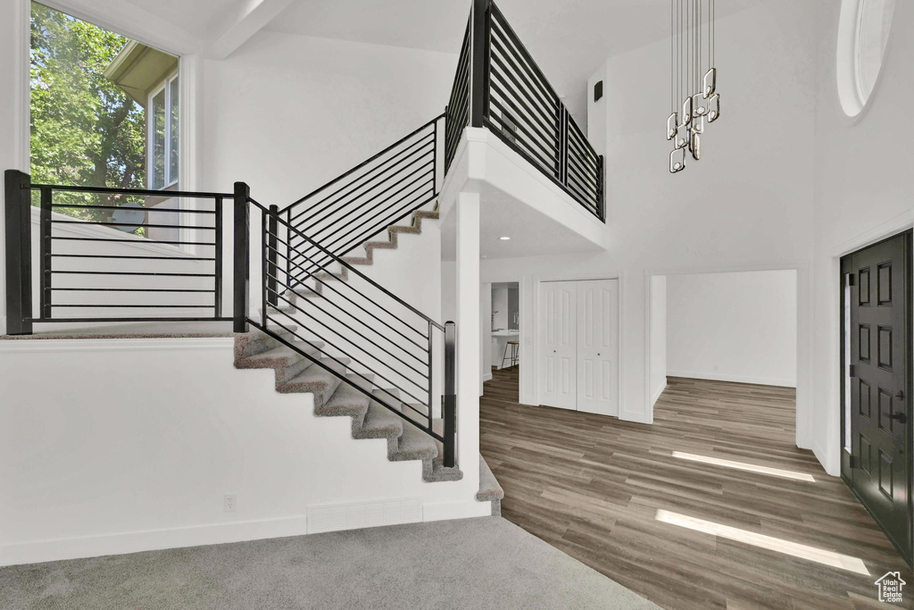 Staircase featuring a towering ceiling, baseboards, and wood finished floors