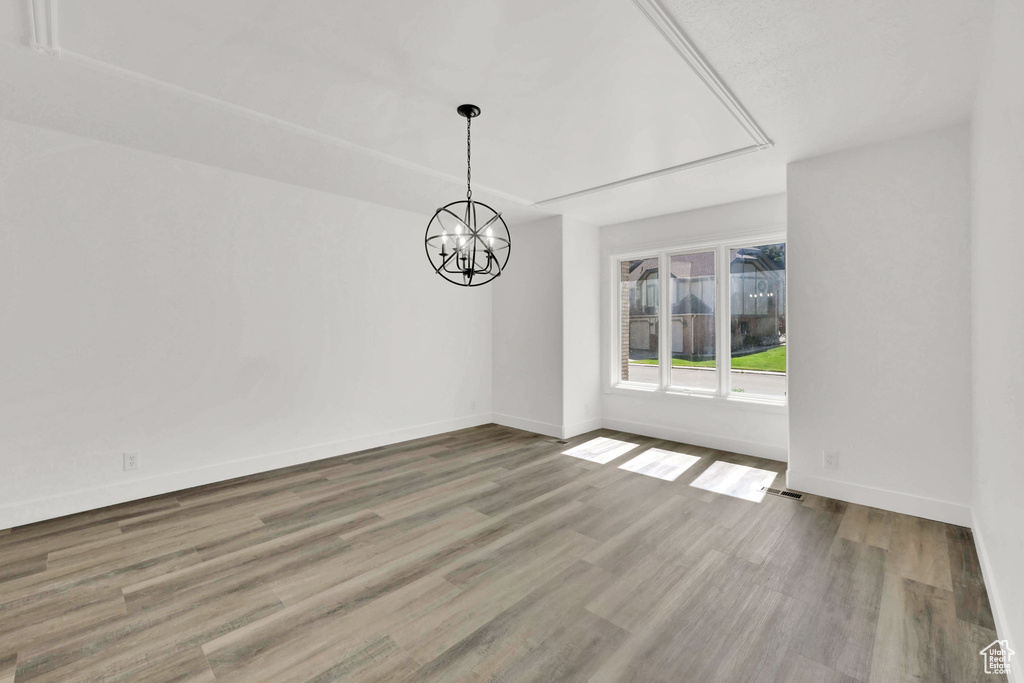 Unfurnished dining area with wood finished floors, baseboards, and a chandelier