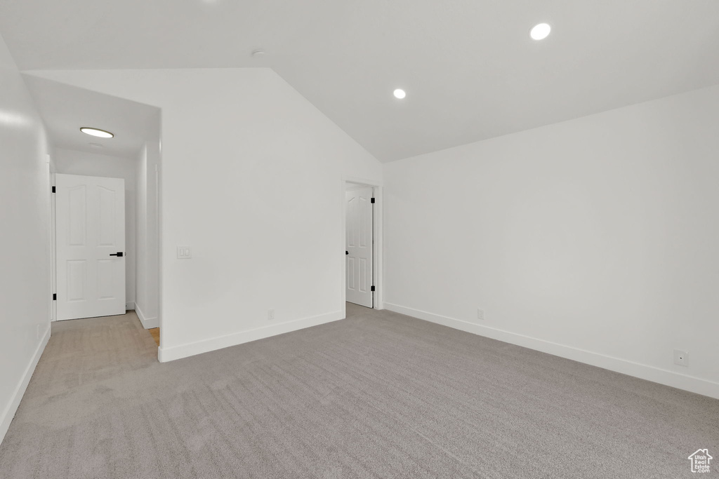 Unfurnished room featuring vaulted ceiling, carpet flooring, baseboards, and recessed lighting