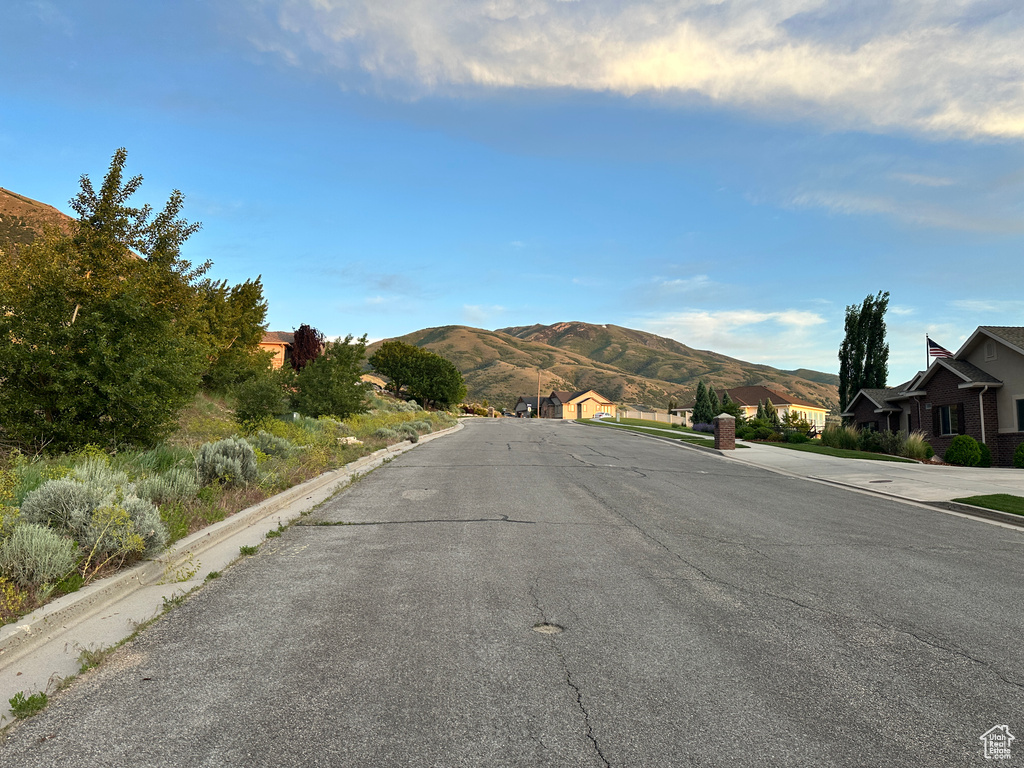 View of asphalt road with a mountain view, curbs, and a residential view