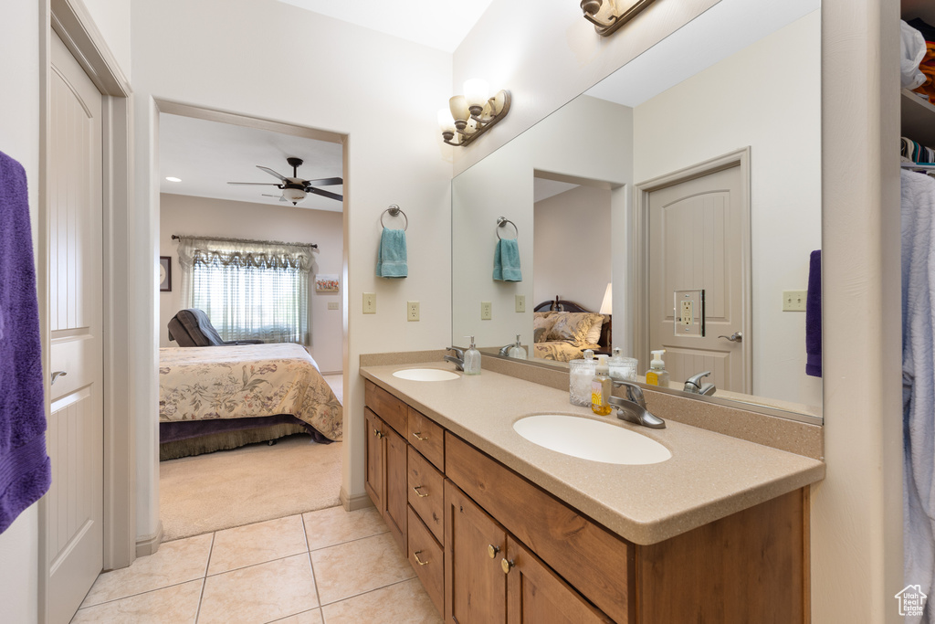 Ensuite bathroom featuring double vanity, tile patterned flooring, and a ceiling fan