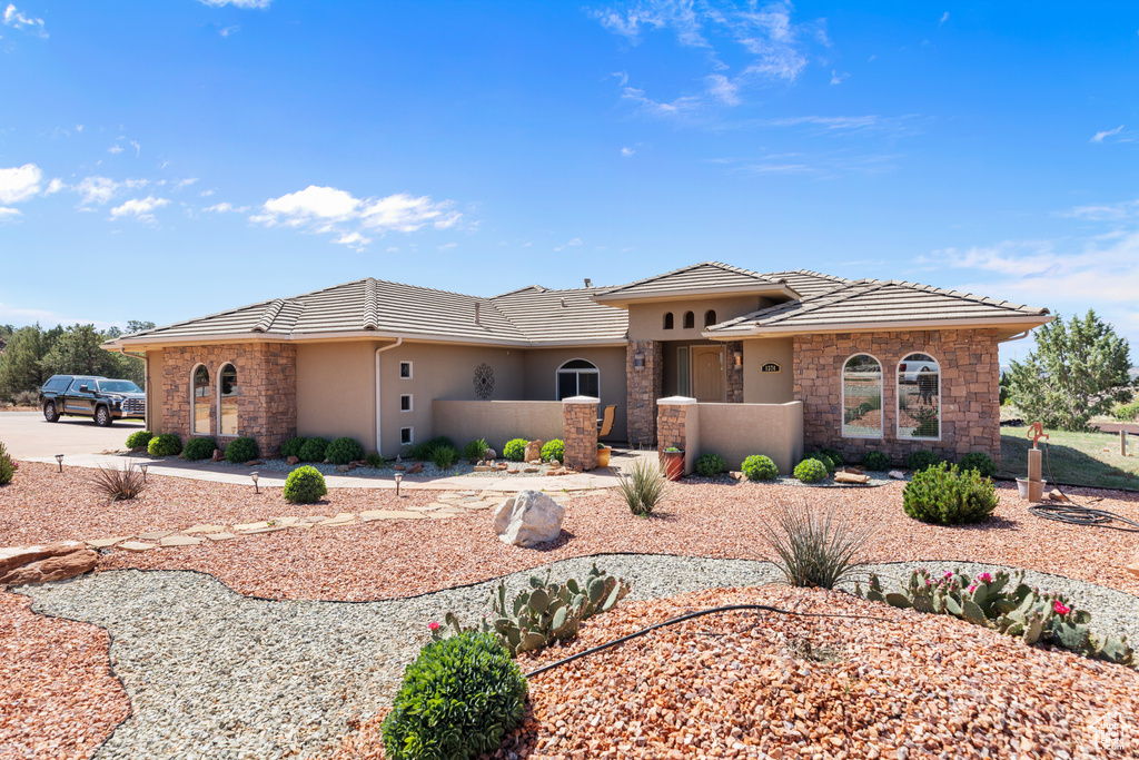View of front of house with stone siding, a tiled roof, and stucco siding
