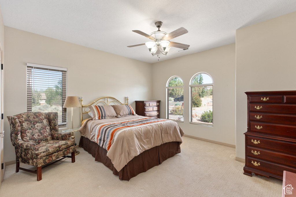 Bedroom featuring multiple windows, light colored carpet, baseboards, and a ceiling fan