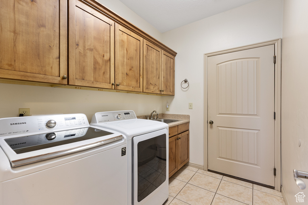 Laundry room featuring washing machine and clothes dryer, cabinet space, and light tile patterned floors