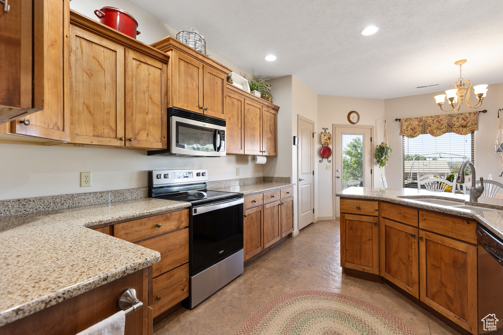 Kitchen featuring stainless steel appliances, a sink, a chandelier, brown cabinetry, and recessed lighting