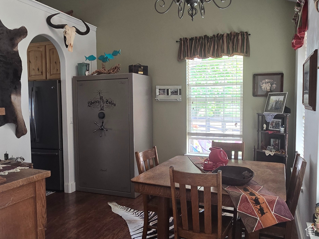 Dining area with wood finished floors, a chandelier, vaulted ceiling, and arched walkways