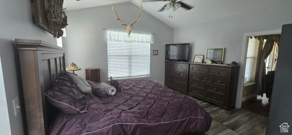 Bedroom with dark wood-type flooring, vaulted ceiling, a ceiling fan, and a fireplace