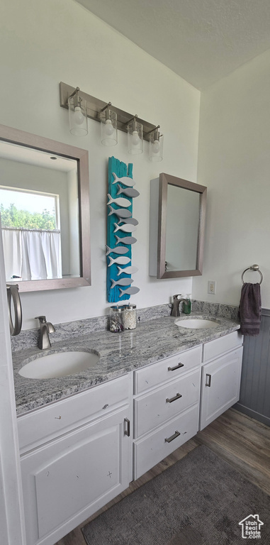 Bathroom with double vanity and wood finished floors