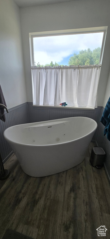 Bathroom featuring wood finished floors, a freestanding bath, and wainscoting
